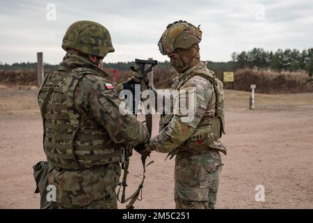 A Polish soldier assigned to the 21st Rifle Brigade instructs a Paratrooper from 3rd Brigade Combat Team, 82nd Airborne Division on a Polish weapon system during a combined training event in Nowa Deba, Poland, Feb. 25, 2022. The focus of the 82nd Airborne Division's mission is to assure our Allies by providing a host of unique capabilities and conducting a wide range of missions that are scalable and tailorable to mission requirements. Stock Photo