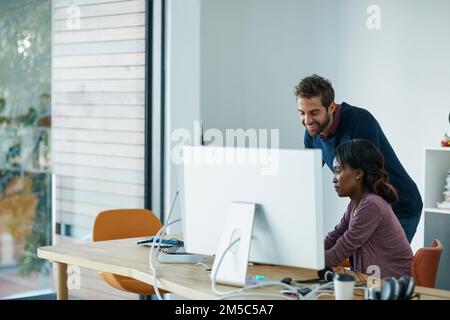 Theyre getting closer to a solution. colleagues working together on a computer in an office. Stock Photo