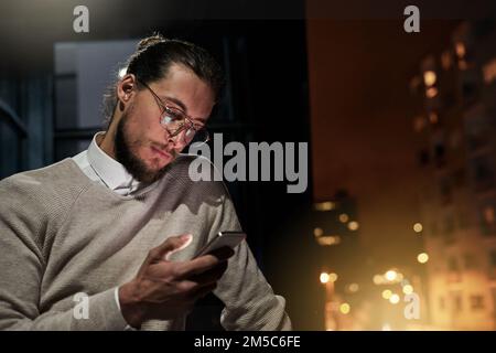 Sending out a late night project update. a handsome young designer working late at the office. Stock Photo