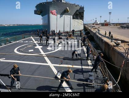 ROTA, Spain (Feb. 28, 2022) – Sailors heave around mooring lines in preparation to depart Naval Station Rota while aboard the Arleigh Burke-class guided-missile destroyer USS Porter (DDG 78), Feb. 28, 2022. Porter, forward-deployed to Rota, Spain, is currently underway in the U.S. Sixth Fleet area of operations in support of regional allies and partners and U.S. national security interests in Europe and Africa. Stock Photo