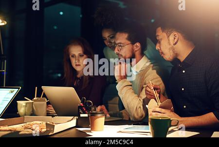 Nothing can derail our productivity on the night shift. a business team using a laptop together on a night shift at work. Stock Photo