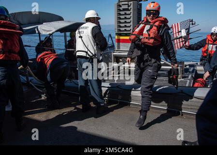 220225-N-XB010-1001 PACIFIC OCEAN (Feb. 25, 2022) Sailors assigned to USS New Orleans (LPD 18) raise a rigid-hull inflatable boat onto the ship using a crane. New Orleans, part of the America Amphibious Ready Group, is operating in the U.S. 7th Fleet area of responsibility to enhance interoperability with allies and partners and serve as a ready response force to defend peace and stability in the Indo-Pacific region. Stock Photo