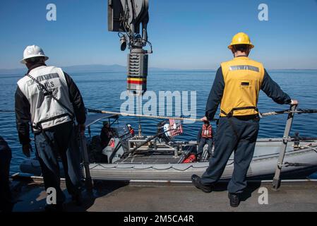 220225-N-XB010-1001 PACIFIC OCEAN (Feb. 25, 2022) Sailors assigned to USS New Orleans (LPD 18) raise a rigid-hull inflatable boat onto the ship using a crane. New Orleans, part of the America Amphibious Ready Group, is operating in the U.S. 7th Fleet area of responsibility to enhance interoperability with allies and partners and serve as a ready response force to defend peace and stability in the Indo-Pacific region. Stock Photo