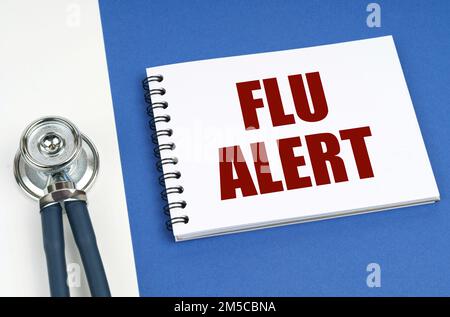 Medical concept. On a blue-white surface lies a stethoscope and a notepad with the inscription - Flu alert Stock Photo