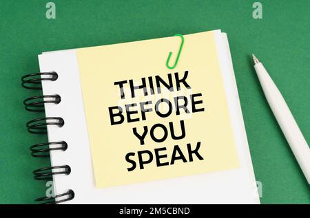 Business concept. On a green surface, a pen, a notepad with stickers and the inscription - THINK BEFORE YOU SPEAK Stock Photo