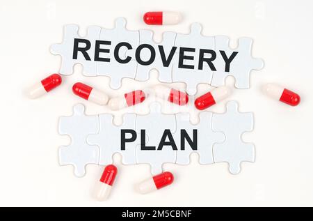 Medical concept. On a white surface, tablets and puzzles with the inscription - RECOVERY PLAN Stock Photo