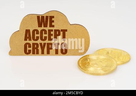 Business and technology concept. Bitcoins lie on a white surface and there is a sign - a cloud with the inscription - We accept crypto Stock Photo