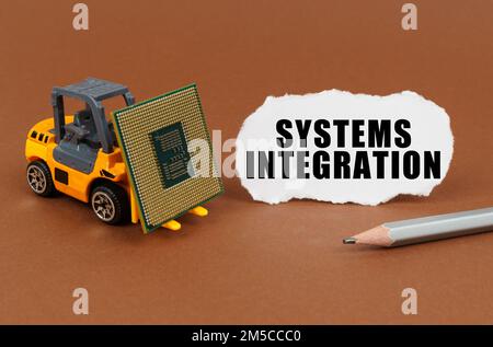 Technological concept. On a brown surface, a forklift is transporting a processor, next to it is paper with the inscription - Systems Integration Stock Photo