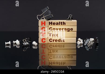 Business concept. On a black reflective surface, buttons, clips and wooden blocks with the inscription - Health Coverage Tax Credit Stock Photo