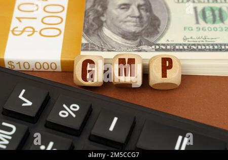 Business concept. On the table are dollars, a calculator and cubes with the inscription - GMP Stock Photo