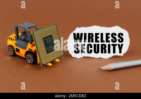 Technological concept. On a brown surface, a forklift is transporting a processor, next to it is paper with the inscription - Wireless Security Stock Photo