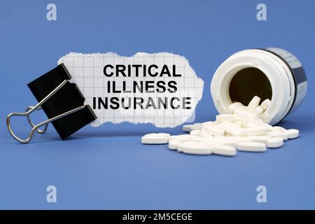 Medicine concept. On the blue surface lies a jar of pills and a clip with paper on which is written - Critical Illness Insurance Stock Photo