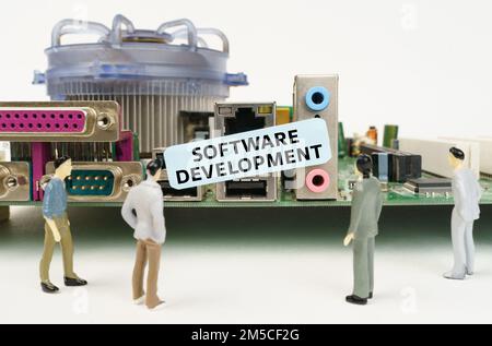 Technology and computer concept. Figures of people are standing near the motherboard and looking at the sticker with the inscription - Software Develo Stock Photo