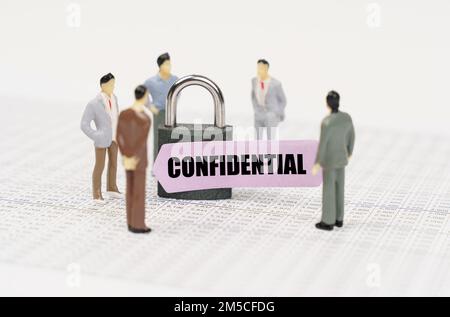 The concept of security in business. There are figures of people on business reports, a padlock with a sticker on which it is written - Confidential Stock Photo