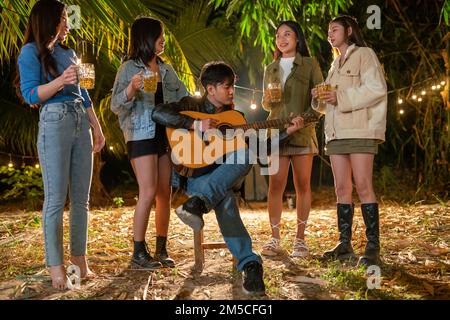 A group of friends at a party enjoy playing guitar at a party. Stock Photo