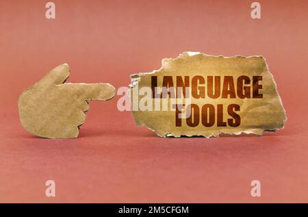 Education concept. On a brown surface, a cardboard hand points to a sign that says - Language Tools Stock Photo