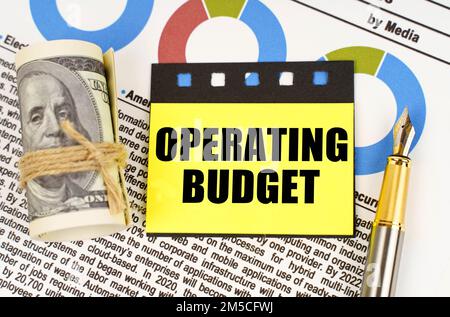 Business concept. On documents with diagrams there are dollars, a pen and yellow stickers with the inscription - Operating budget Stock Photo