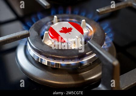 Gas import and export concept. A burning gas burner of a home stove, in the middle of which a flag is depicted - Canada Stock Photo