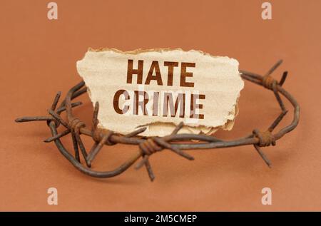 The concept of law and crime. On a brown surface, barbed wire and a cardboard sign with the inscription - hate crime Stock Photo