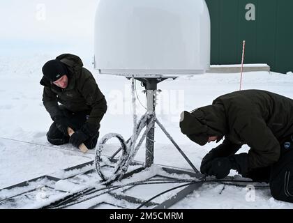 220302-N-JO245-1023 PRUDHOE BAY, Alaska (March 2, 2022) – Bruce Billian (left) a chief scientist, and Tyler Brant, an engineer, assigned to Naval Information Warfare Center Atlantic, removes snow from satellite communications equipment in Prudhoe Bay, Alaska. Billian and Brant tested the gear in northern Alaska’s extreme cold before moving it up to Ice Camp Queenfish during the U.S. Navy’s Ice Exercise (ICEX) 2022. ICEX 2022 is a three-week exercise that allows the Navy to assess its operational readiness in the Arctic, increase experience in the region, advance understanding of the Arctic env Stock Photo