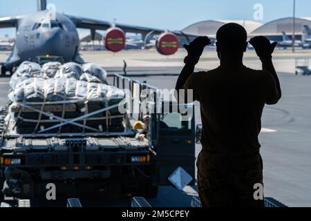 Airman 1st Class Jovanni Bauchi, 535th Airlift Squadron loadmaster, directs a Tunner 60K aircraft cargo loader/transporter transporting cargo onto a C-17 Globemaster III during Exercise TROPIC FURY at Joint Base Pearl Harbor-Hickam, Hawaii, March 2, 2022. The first phase of the exercise emphasizes JBPHH Air Force readiness to combat future operations in the Pacific region by showing its capability to deploy equipment and aircraft anytime, anywhere. Stock Photo