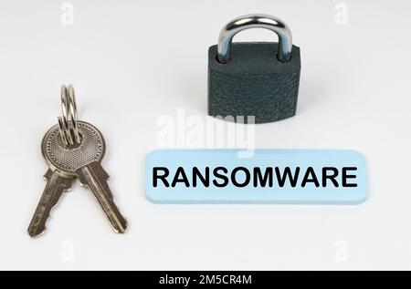 The concept of security in business. On a white surface there is a lock, keys and a blue sign with the inscription - Ransomware Stock Photo