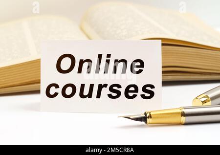 Education concept. Against the background of the book lies a pen and a business card with the inscription - online courses Stock Photo