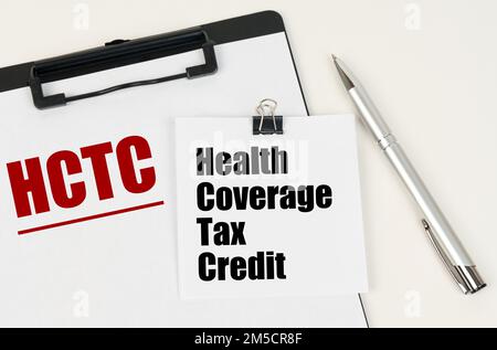 Business concept. On the tablet is a sheet of paper with the inscription - HCTC and stickers with the inscription - Health Coverage Tax Credit, next t Stock Photo