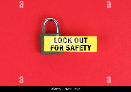 Business and security concept. On the red surface there is a lock with a sticker with the inscription - lock out for safety Stock Photo