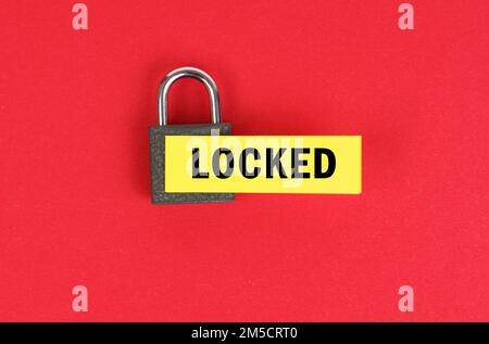 Business and security concept. On the red surface there is a lock with a sticker with the inscription - locked Stock Photo