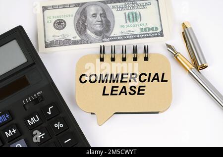 Business concept. On a white surface, a calculator, dollars, a pen and a sign with the inscription - COMMERCIAL LEASE Stock Photo