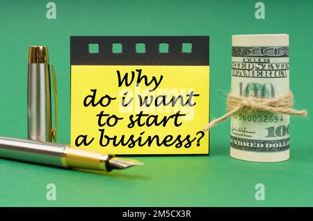 Business concept. On a green surface, a pen, dollars, a notepad and yellow stickers with the inscription - Why Do I Want to Start a Business Stock Photo