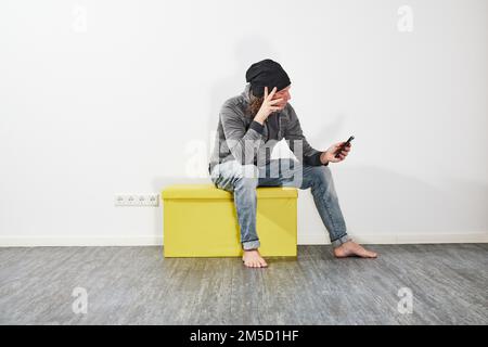 Man using his smartphone on a green box Stock Photo