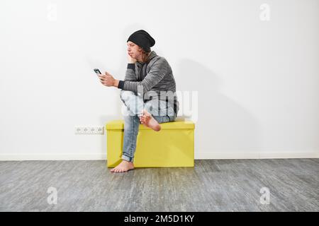 Man using his smartphone on a green box Stock Photo