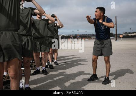 U.S. Marine Corps Staff Sgt. Alex Guerrero, a drill instructor with Kilo Company, 3rd Recruit Training Battalion, gives instructions to recruits following a circuit course event at Marine Corps Recruit Depot San Diego, Mar. 3, 2022. Drill instructors are responsible for ensuring the recruits are properly hydrated before and after every event. Stock Photo