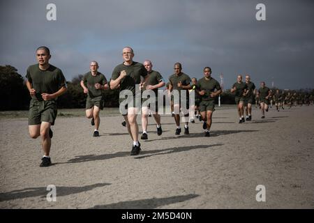 U.S. Marine Corps recruits with Kilo Company, 3rd Recruit Training Battalion, conduct a run during a circuit course event at Marine Corps Recruit Depot San Diego, Mar. 3, 2022. Recruits were required to run one mile on a dirt track prior to conducting the course. Stock Photo