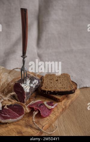 Close-up piece of jamon on fork, light appetizer, homemade food, selective focus Stock Photo