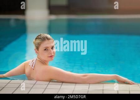 I could get used to this. Portrait of a young woman relaxing in the pool at a spa. Stock Photo