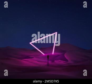 Modern futuristic neon abstract background. Large triangle glowing purple object in the center of sand dune and lonely woman silhouette walking in the Stock Photo