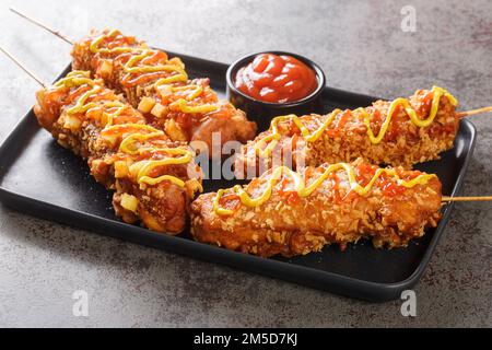 Korean corn dogs or Korean hot dogs are popular local street food, typically made of sausages or mozzarella cheese on sticks deep-fried closeup on the Stock Photo