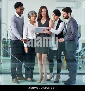 Taking a preview at a plan theyve been developing. a group of colleagues working together on a digital tablet in a modern office. Stock Photo