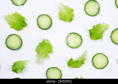 vegetable background of lettuce leaves, cucumber slices, on a white background. The concept of proper nutrition.  Stock Photo