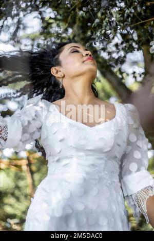 Attractive Sri Lankan female wearing white dress and posing in the park Stock Photo