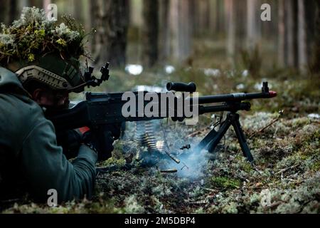 20220303-A-VU095-1515 – A Latvian National Guard soldier fires an M-240B machine gun during an ambush training exercise in the forests of Latvia, March 3, 2022. The bilateral training between Latvia and U.S. Army 10th Special Forces Group creates interoperability with NATO allies, improves military readiness, and strengthens joint confidence while promoting peace and stability within the region. Stock Photo