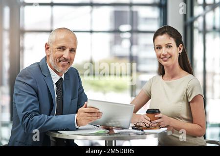 We share the same passion for excellence. Portrait of two businesspeople working together on a digital tablet in a modern office. Stock Photo