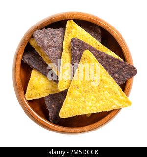 Yellow and blue tortilla chips, in wooden bowl. Snack food made from corn tortillas cut into triangle shaped wedges, deep fried and slightly salted. Stock Photo