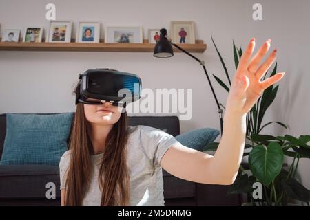 Young woman using virtual reality equipment, VR glasses, to look around the artificial world Stock Photo