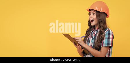 Renovation child, surprised teen girl in construction helmet making notes in clipboard, check results. Child builder in helmet horizontal poster Stock Photo