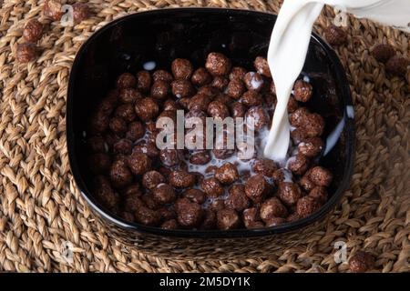 photo quick chocolate cereal balls with milk poured on top Stock Photo