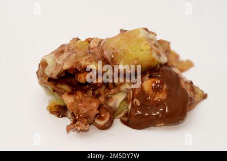 Sweet chocolate mix rolls stuffed with banana fruit pieces, nuts, hazelnuts, raisins, white and brown chocolate sauce with toppings of white and dark Stock Photo